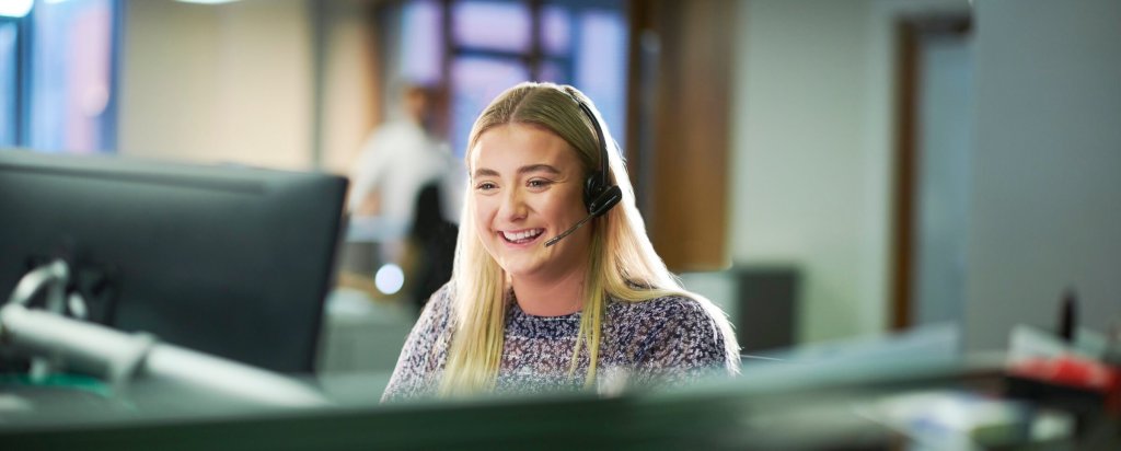A control room operator smiling as she takes a call on a headset.