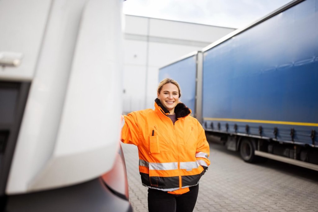 A woman in a hi-vis jacket standing beside a lorry.