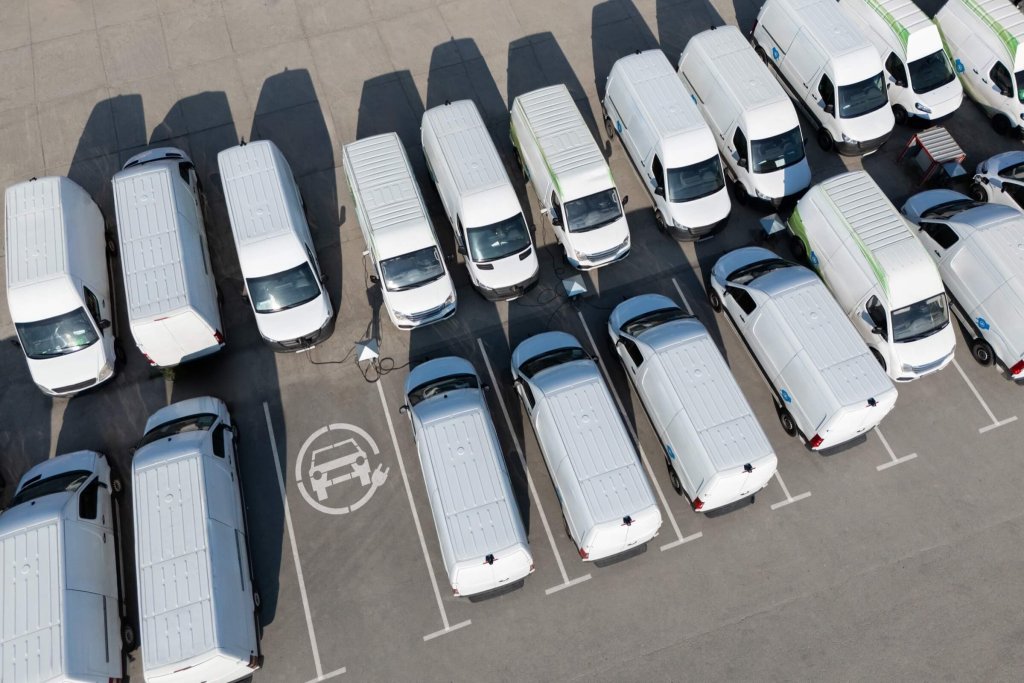 An aerial view of white vans parked in rows.