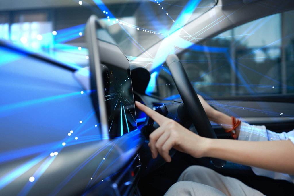 A driver touching a vehicle display with glowing lines suggesting driver-assistance technology.