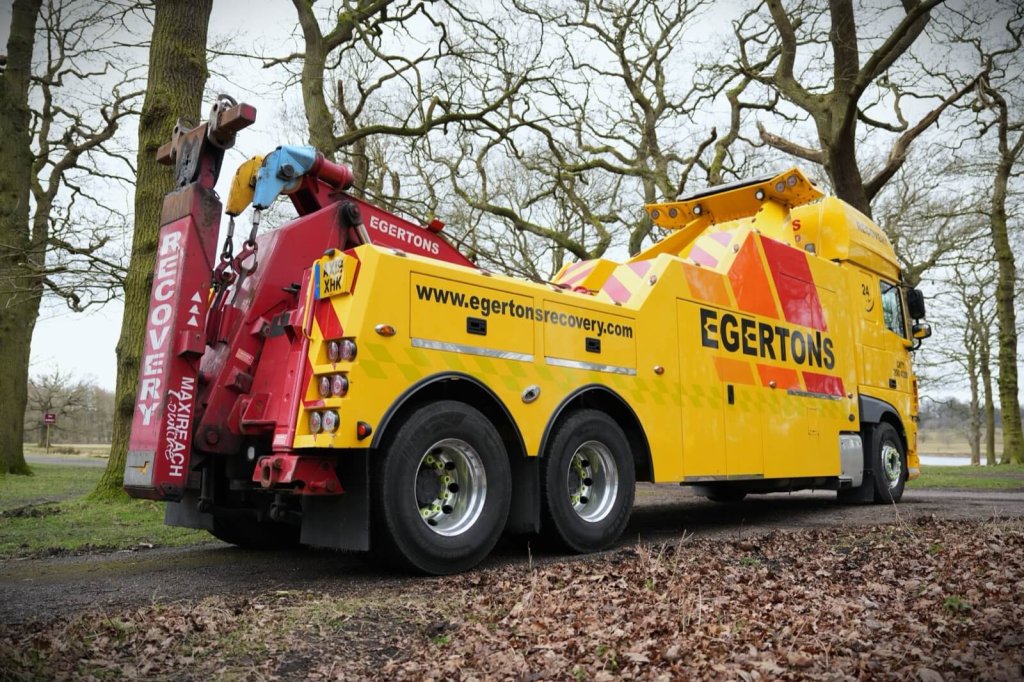An Egertons heavy recovery truck parked among trees.