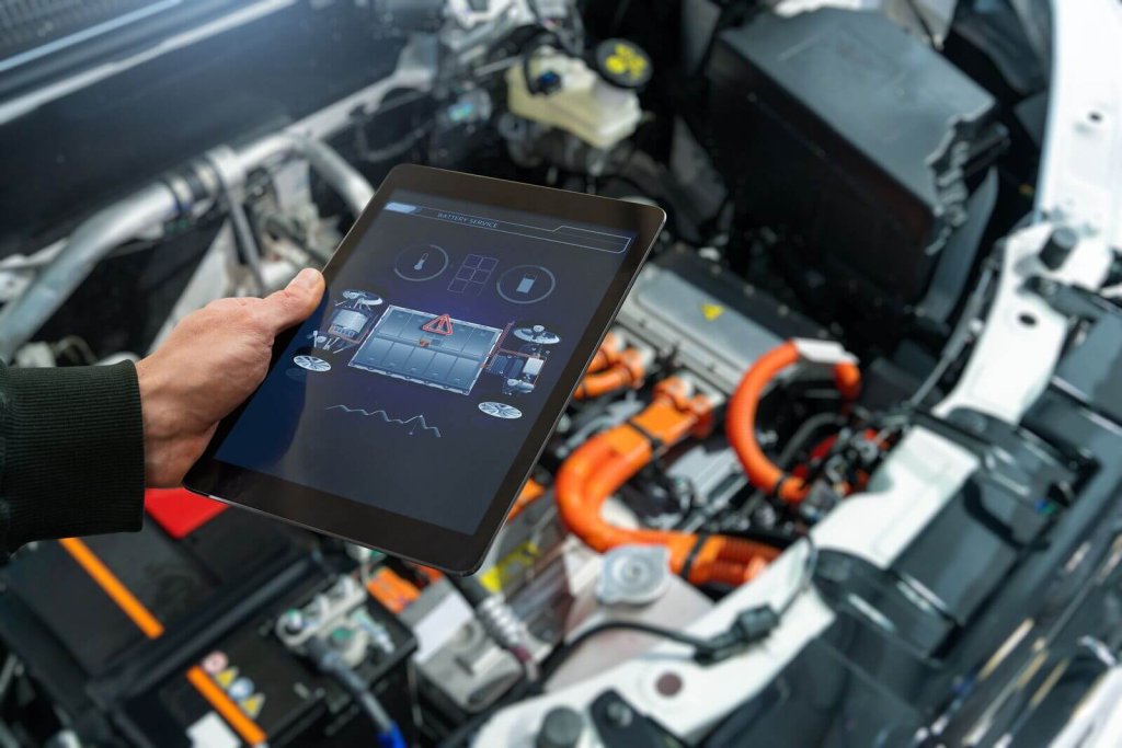 Technician running diagnostics on an electric vehicle with a tablet.