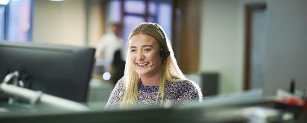 Smiling call handler wearing a headset at her desk.
