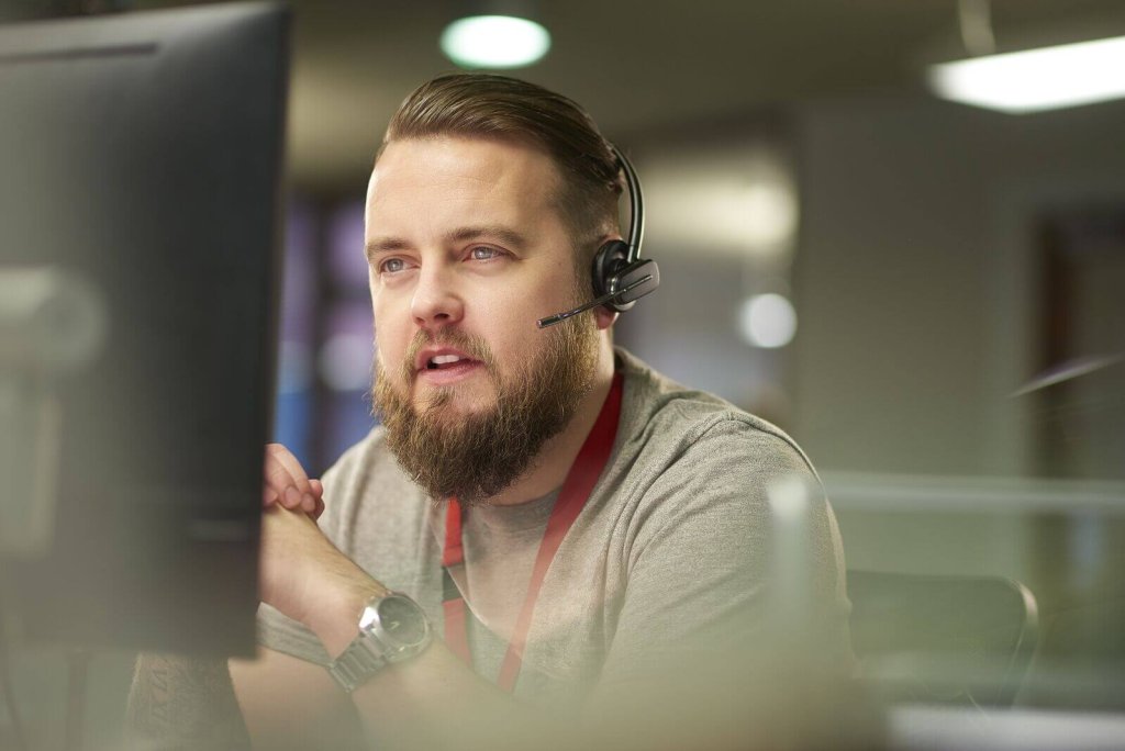 Call handler with a headset taking a call at his desk.