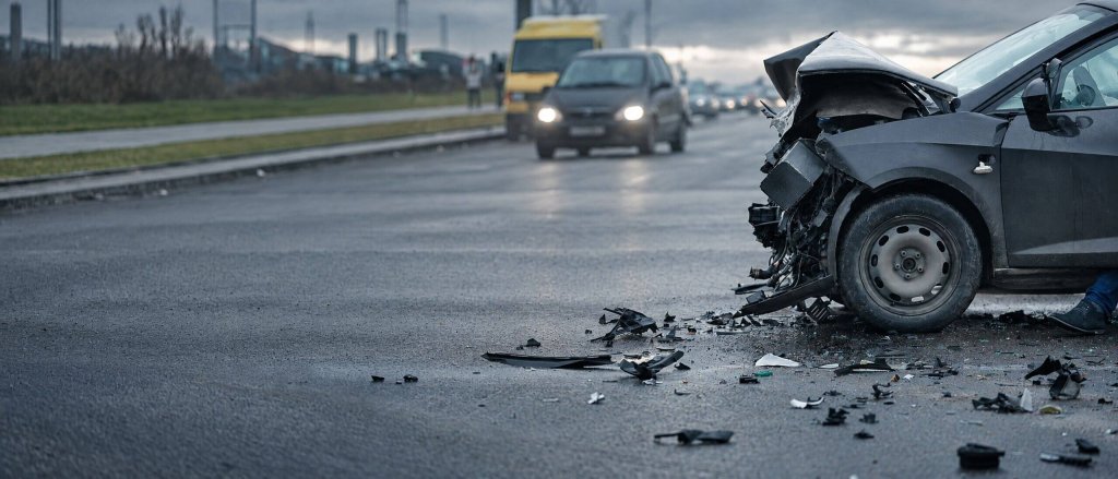 Damaged car and debris on the road after a collision.