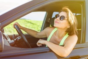 Smiling woman driver, driving black SUV, summer trip